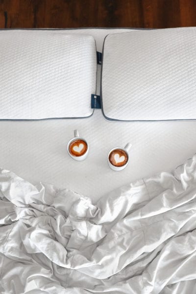 Two delicious cups of premium coffee on a Nestled organic mattress topper.