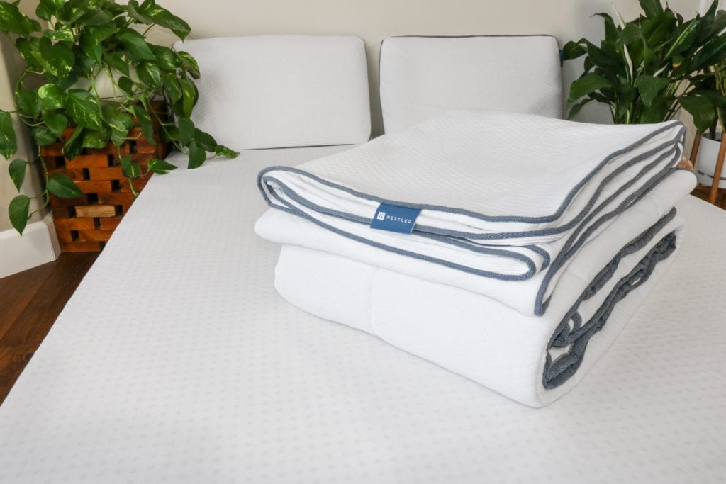 Nestled mattress covers folded on a covered mattress topper.