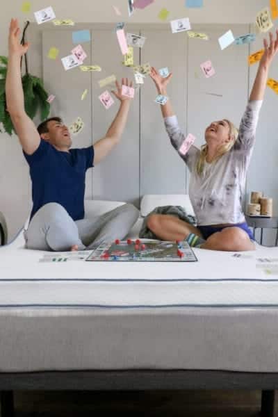 Young couple playing a board game on a Naturally Nestled organic latex mattress topper.