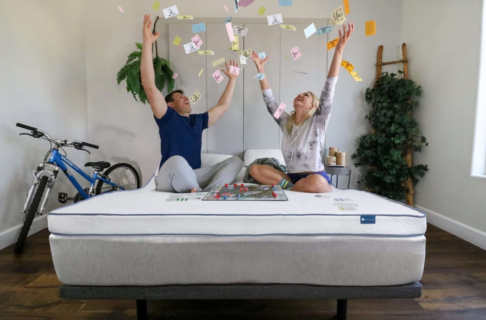 Young couple playing a board game on a Naturally Nestled organic latex mattress topper.