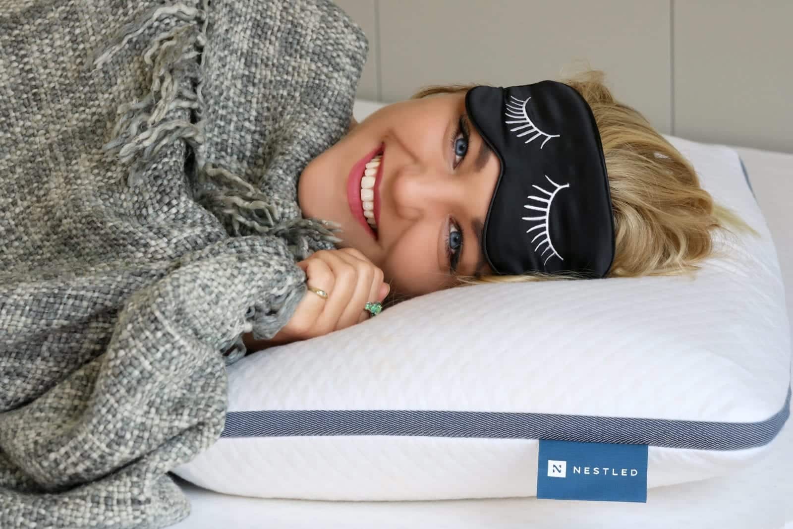 Woman smiling while laying on her Naturally Nestled pillow.