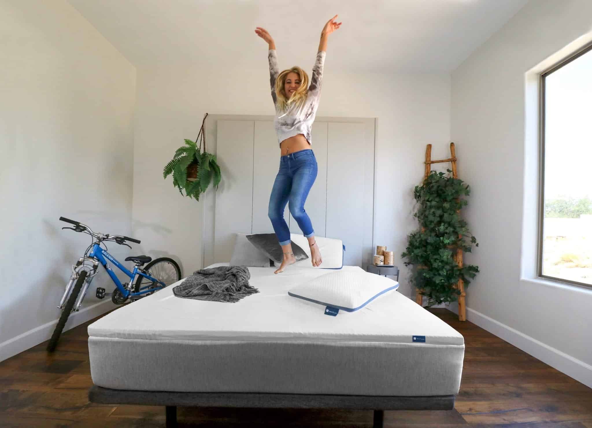 A girl jumping on a Naturally Nestled latex mattress topper