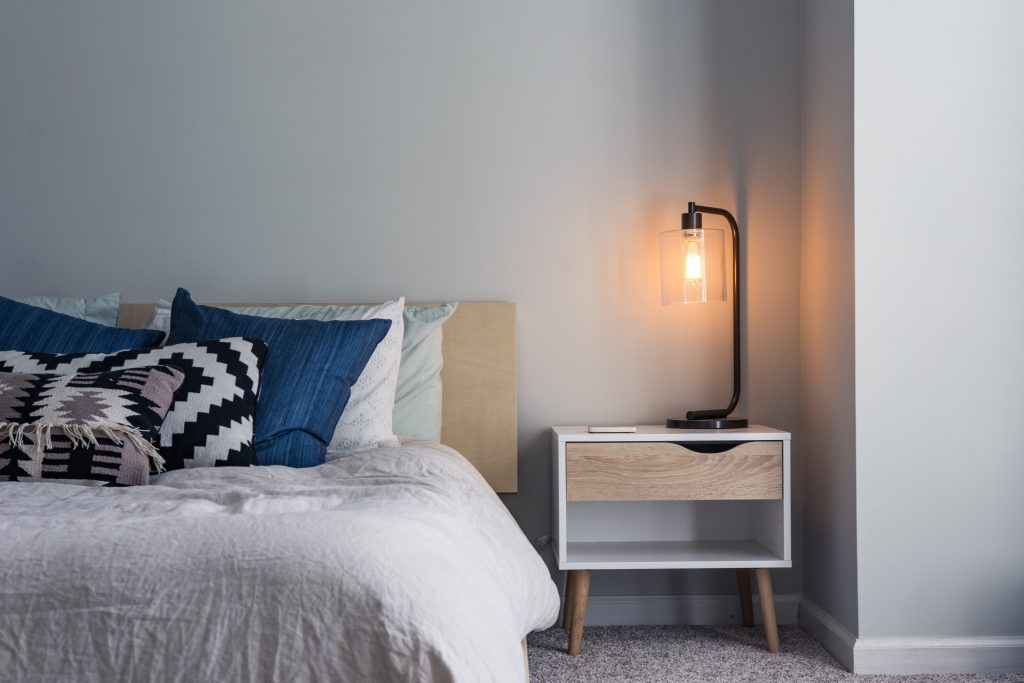 a bed with a side table and lamp beside it