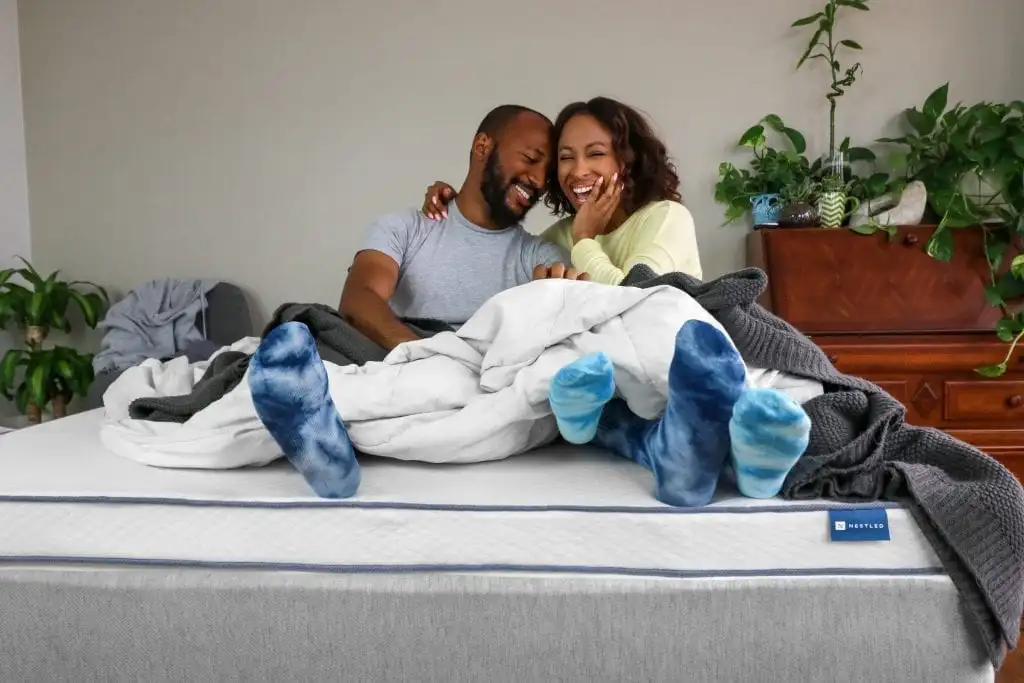 A couple sits comfortably on an eco-friendly mattress topper from Naturally Nestled