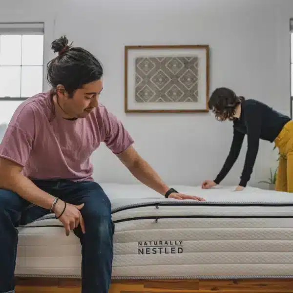 A man sits on a new mattress and tests it for comfort