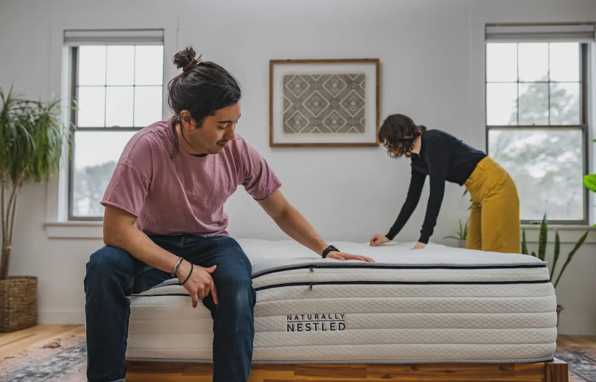 A man sits on a new mattress and tests it for comfort
