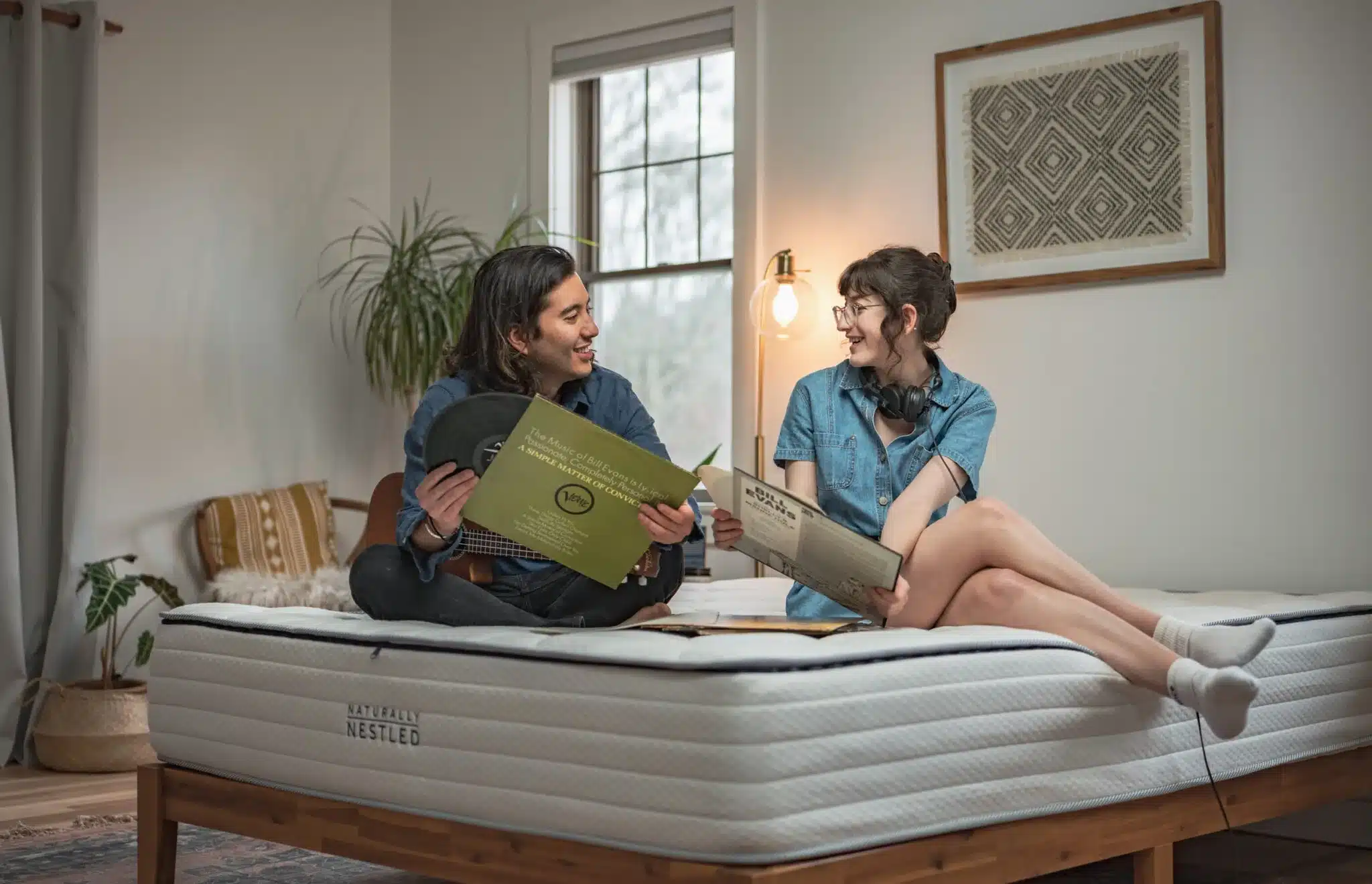 A couple sits on a mattress looking at records