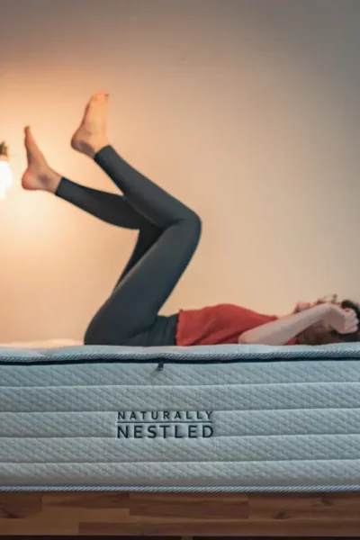 A woman lies on an organic mattress with her feet up