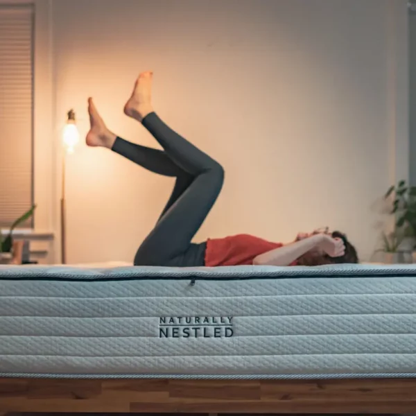 A woman relaxes on the best mattress for osteoporosis with her feet up in the air