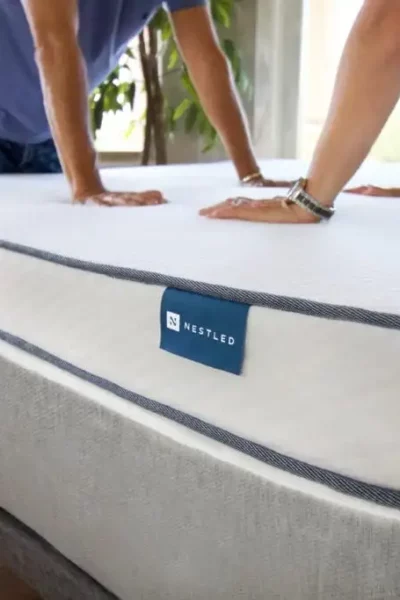 Two people use their arms to test a mattress from Naturally Nestled for support