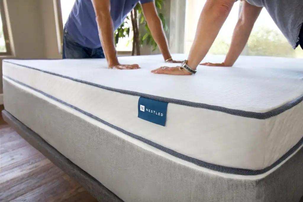 Two people use their arms to test a mattress from Naturally Nestled for support