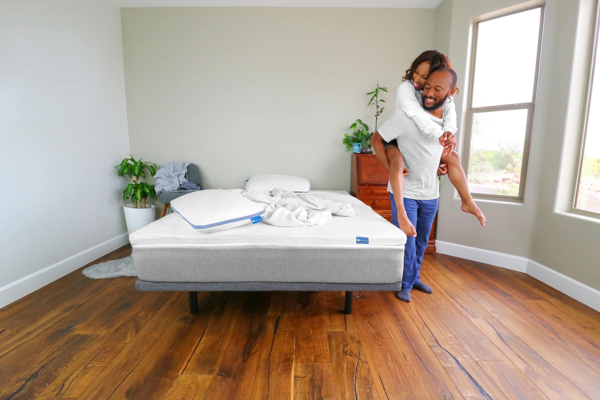 A couple stands and smiles at their most durable mattress from Naturally Nestled