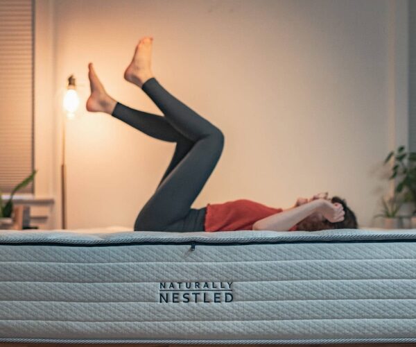 A woman lies on a latex mattress for chronic pain with her feet up in the air