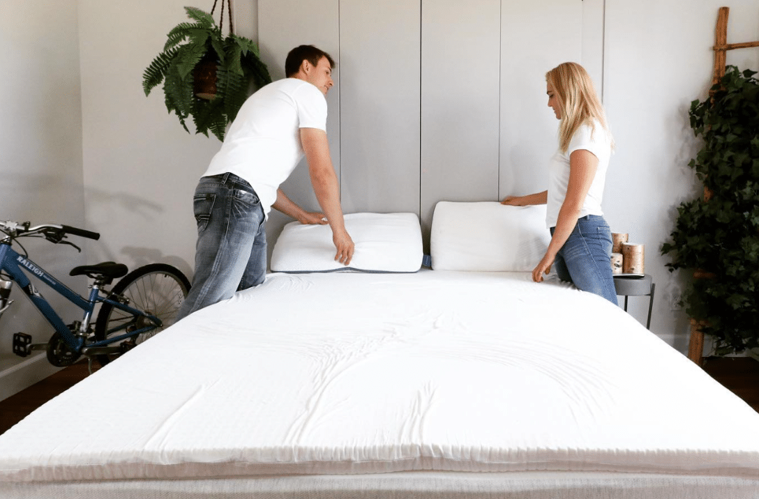 A man and a woman making a bed