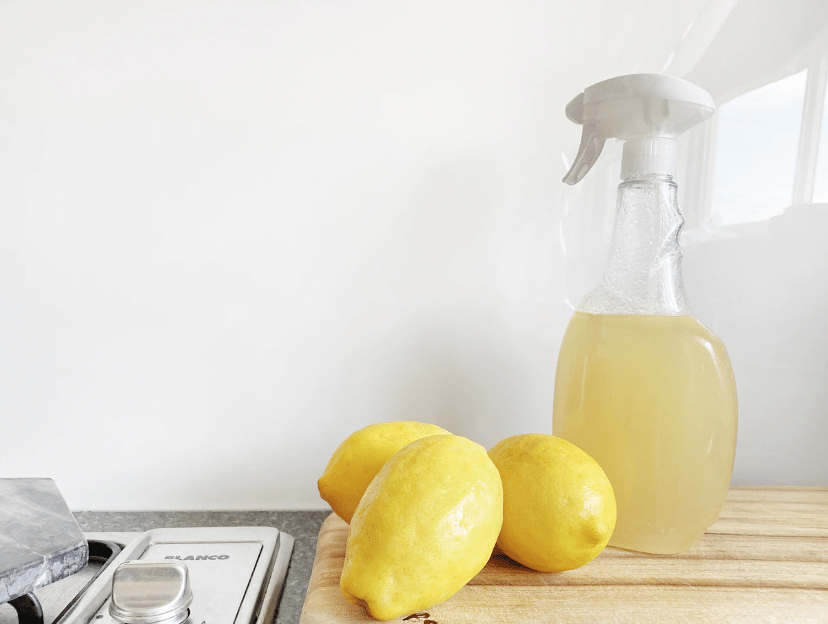 A few lemons lie next to a spay bottle of white vinegar as a way to get cigarette smell out of a mattress