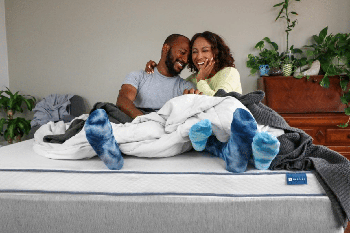 A couple sits comfortably on a mattress topper from Naturally Nestled
