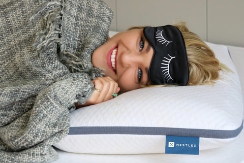 A happy woman with an eye mask waking up cheerfully after a night’s rest on a natural latex pillow