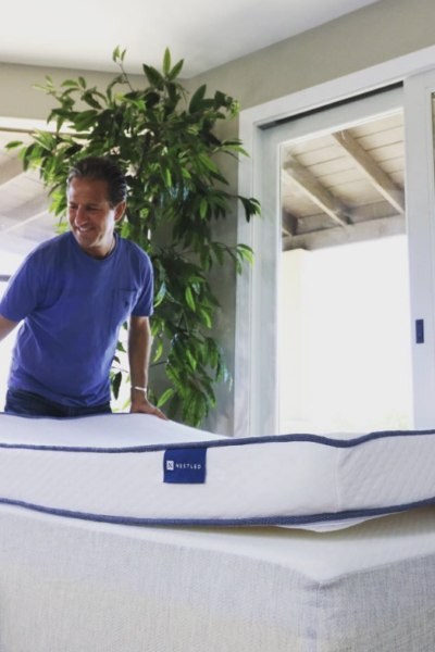 Two people move a mattress while wondering if there’s fiberglass in mattresses