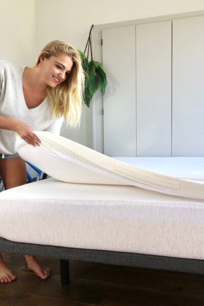 Young woman adjusts a mattress topper