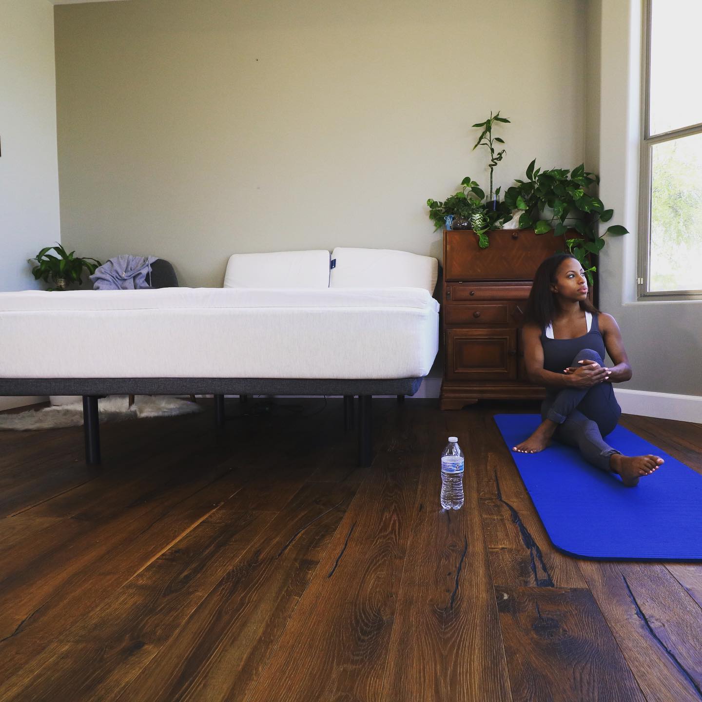 Woman on a blue yoga mat next to a bed